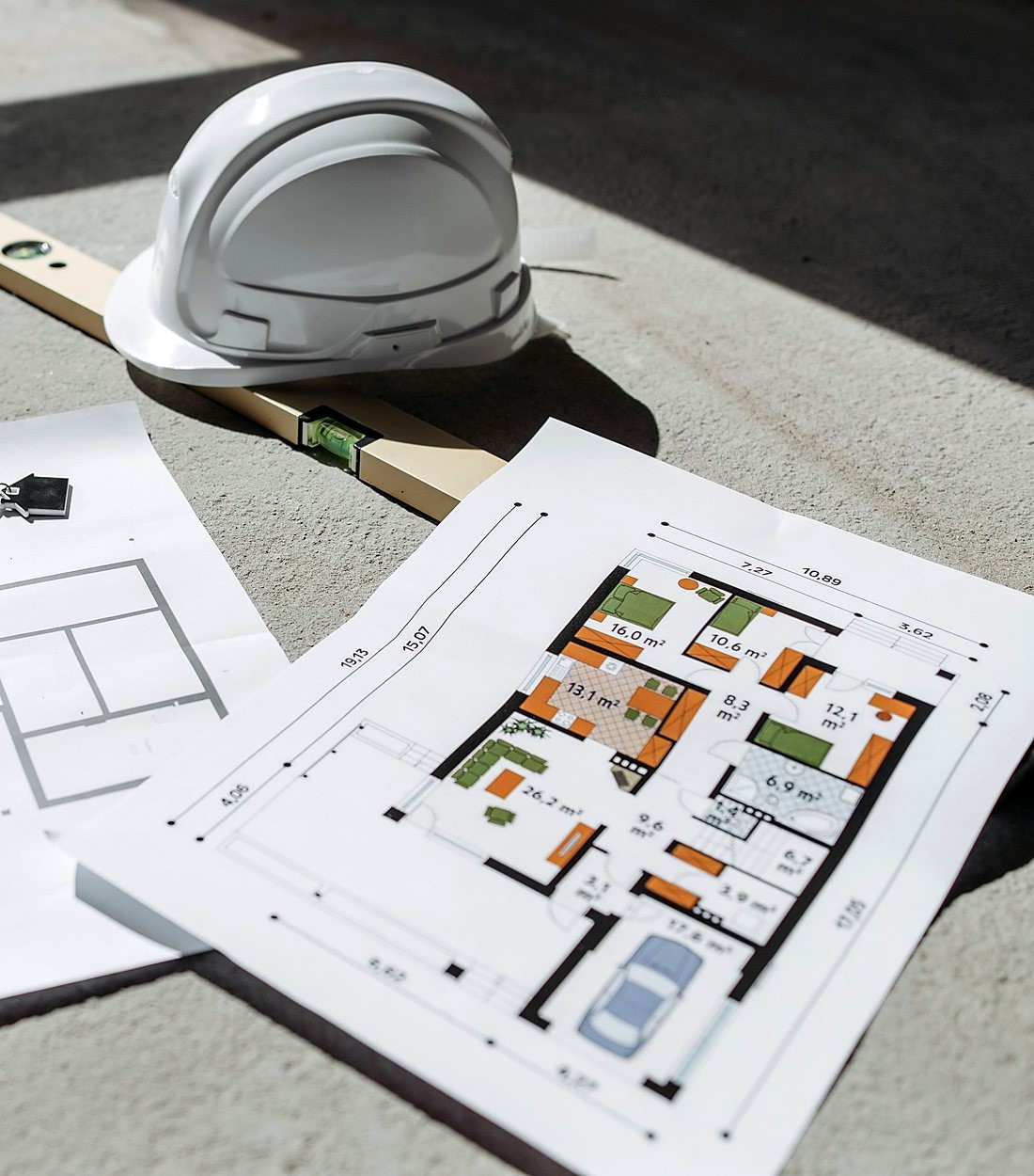 home-abertura Capacete, nível e planta baixa sobre o piso de uma obra